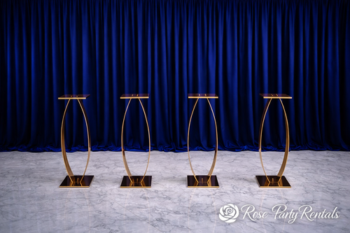 Gold oval pedestals against navy drapery